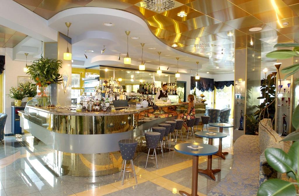 un bar dans un restaurant avec des chaises et un comptoir dans l'établissement Hotel Luna, à Bibione