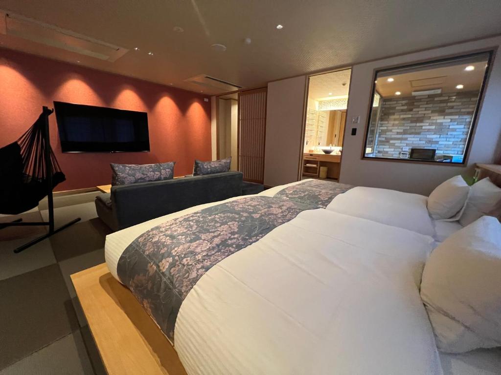 une chambre avec un grand lit blanc et un canapé dans l'établissement Ikeda Onsen Ryokan Tachikawa, à Ōgaki