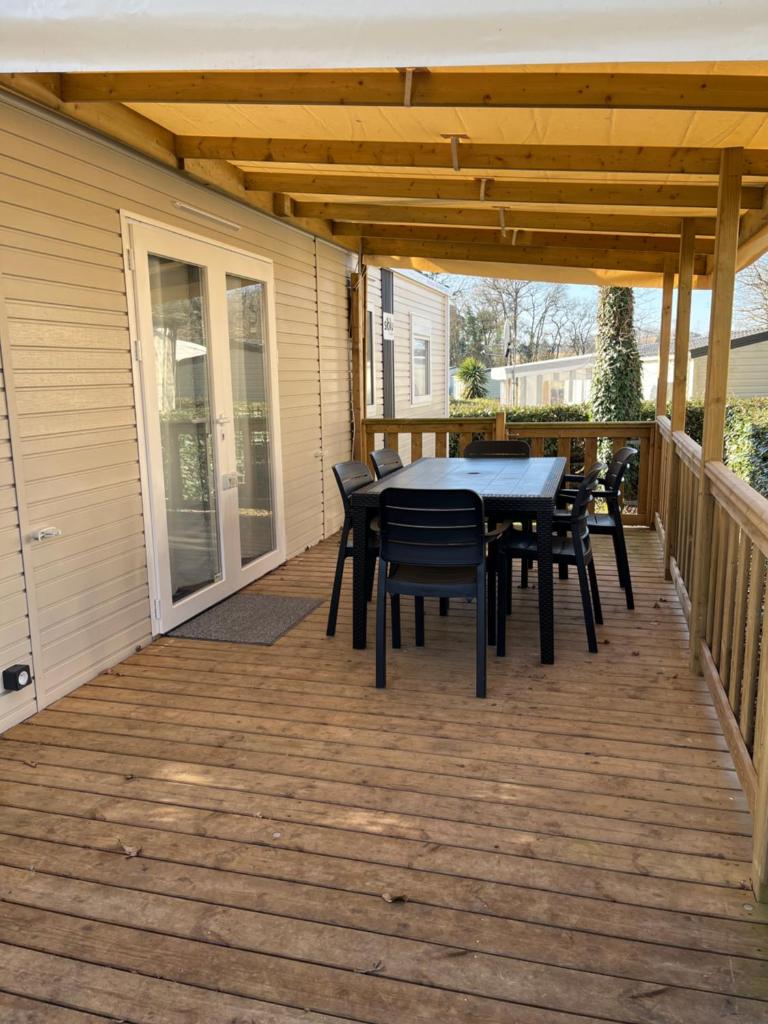un patio avec une table et des chaises sur une terrasse dans l'établissement Mobilhome bora bora, à Pont-Aven