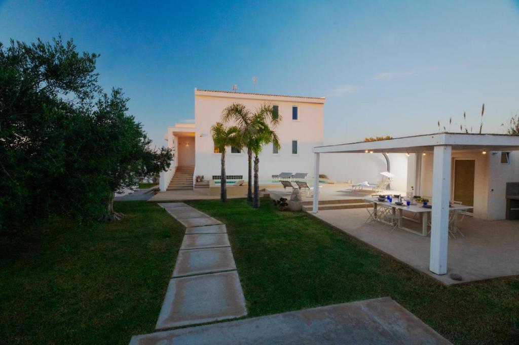 un jardin avec une terrasse et un bâtiment dans l'établissement Villa Delia, à Mazara del Vallo