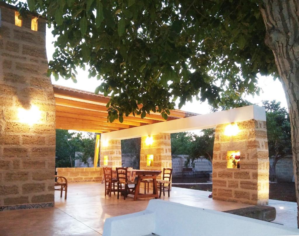 un patio avec une table et des chaises sous un arbre dans l'établissement Gallipoli Salento Antica Dimora con piscina ad uso esclusivo, à Parabita