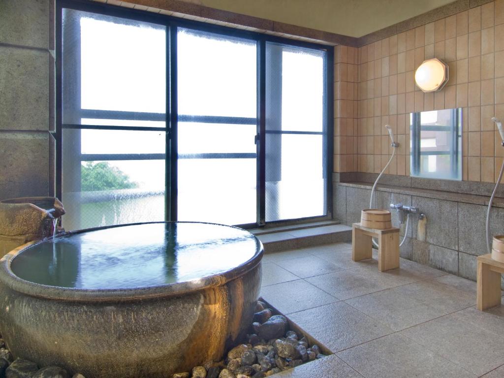 La salle de bains est pourvue d'une grande baignoire et d'une grande fenêtre. dans l'établissement Kishigon Ryokan, à Shibukawa