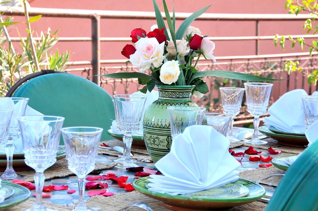 une table avec un vase rempli de fleurs et de verres dans l'établissement Riad Lila, à Marrakech