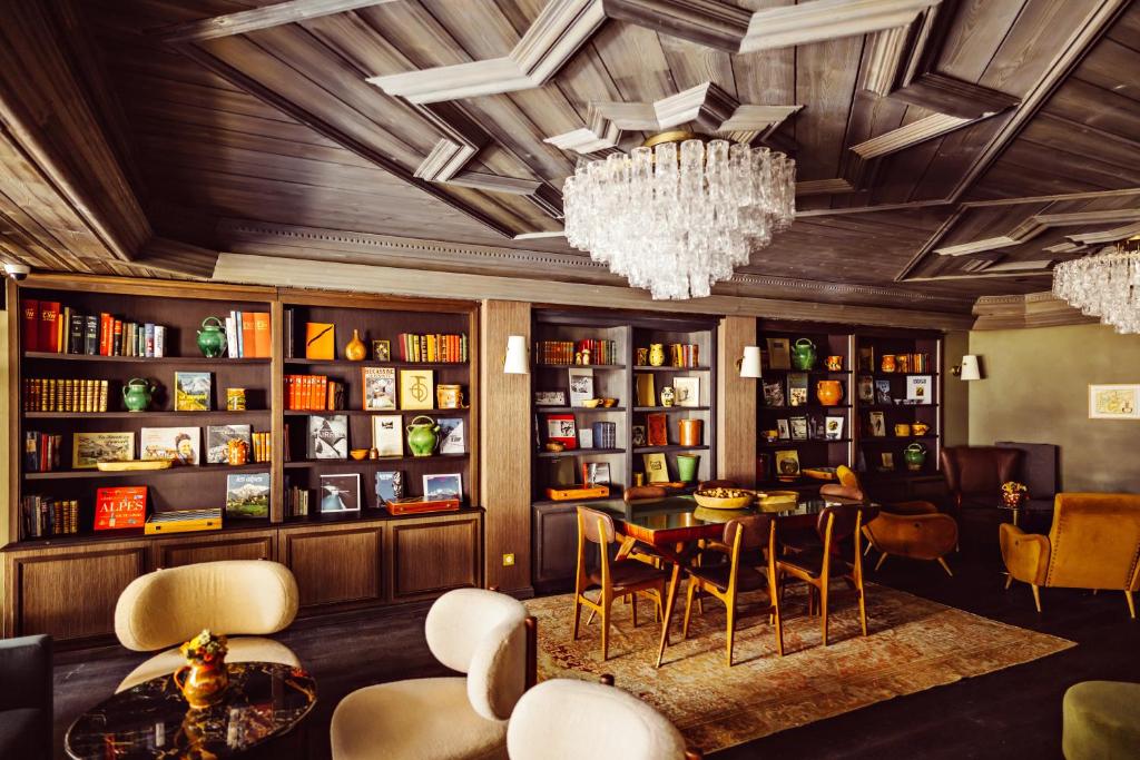 une bibliothèque avec une table, des chaises et un lustre dans l'établissement Le Fitz Roy, a Beaumier hotel, à Val Thorens