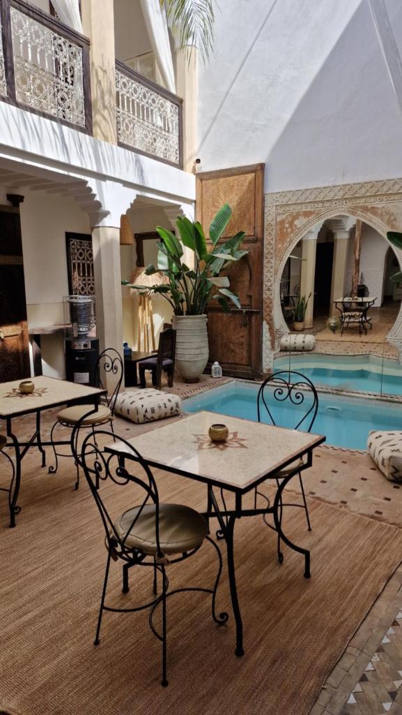 - un salon avec deux tables et une piscine dans l'établissement Riad Des Arts, à Marrakech