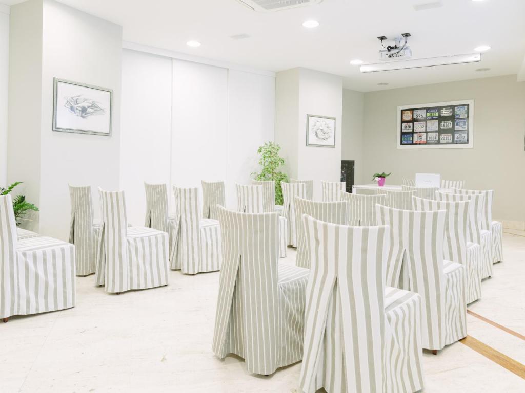 une rangée de chaises blanches dans une pièce dans l'établissement Hotel Sporting, à San Benedetto del Tronto 34 autres photos