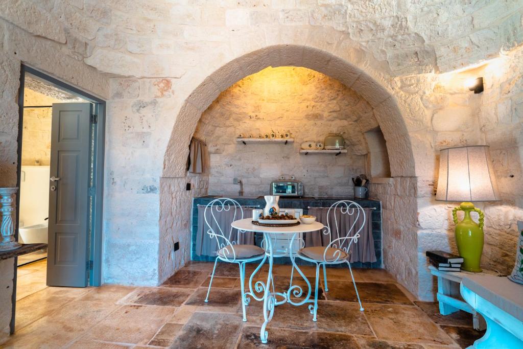 une cuisine avec une table et des chaises dans un mur en pierre dans l'établissement WePuglia - Trullo Meraviglioso, à Martina Franca