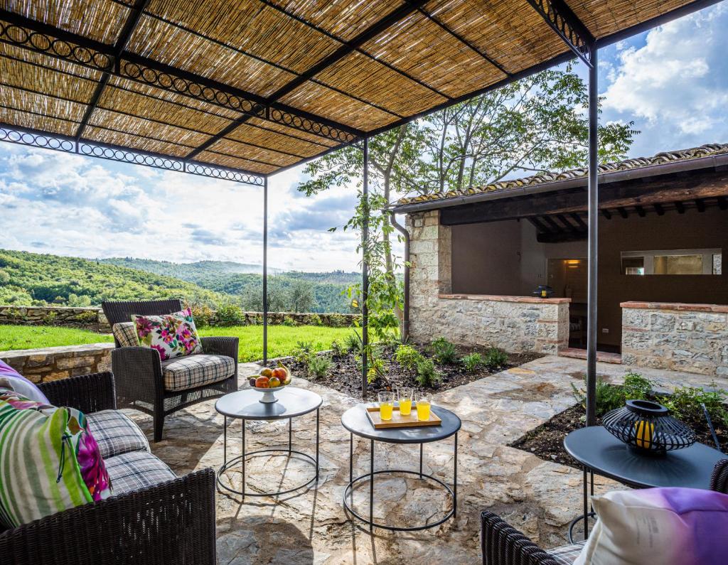 une terrasse avec des tables et des chaises ainsi qu'une cheminée dans l'établissement Casa all'Erta, villa with private pool, à Gaiole in Chianti