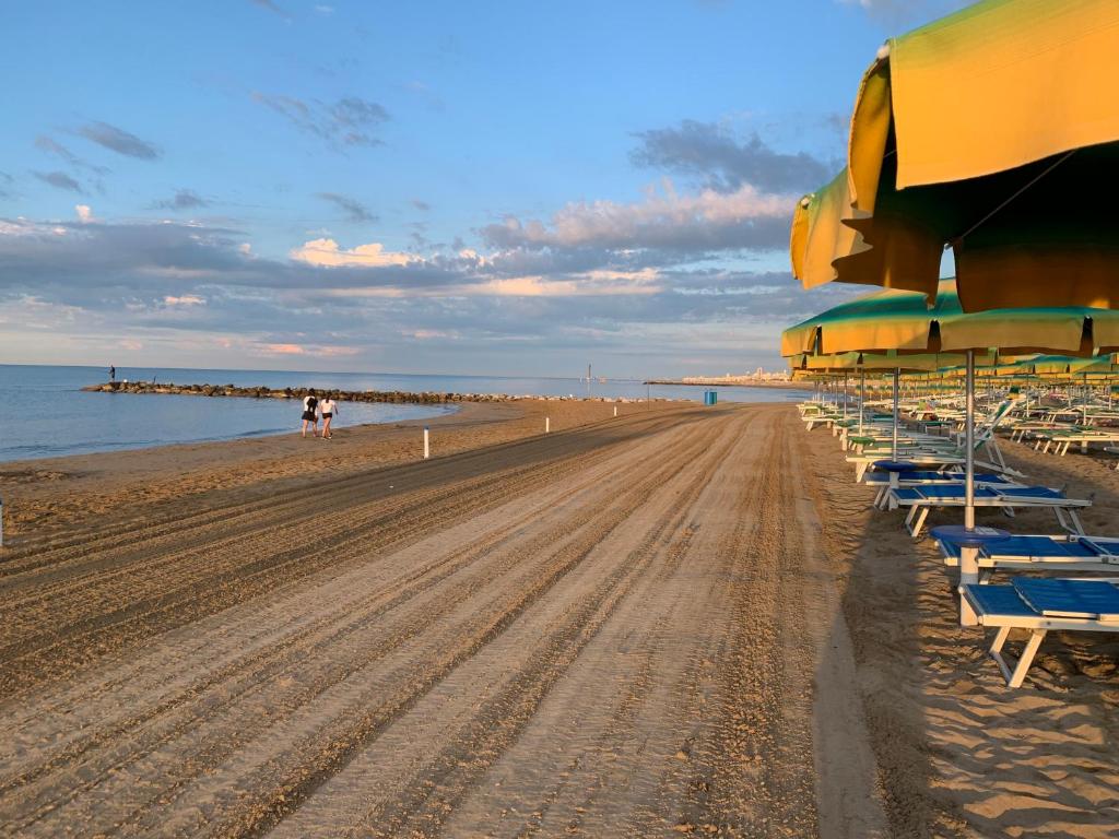- une plage avec un bouquet de chaises et de parasols dans l'établissement Hotel Beau Rivage Pineta, à Lido di Jesolo
