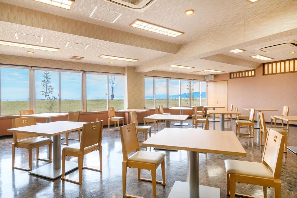 une salle à manger avec tables, chaises et fenêtres dans l'établissement Umino Hotel Hajime, à Beppu