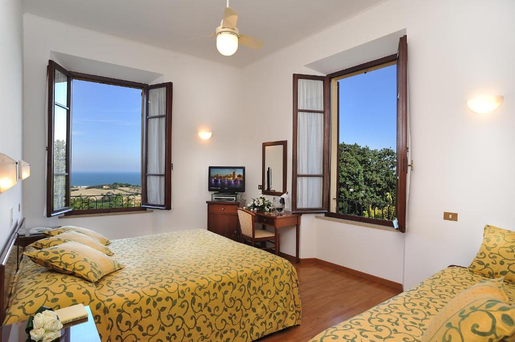 une chambre avec deux lits et deux fenêtres dans l'établissement Hotel Bel Sit, à Senigallia