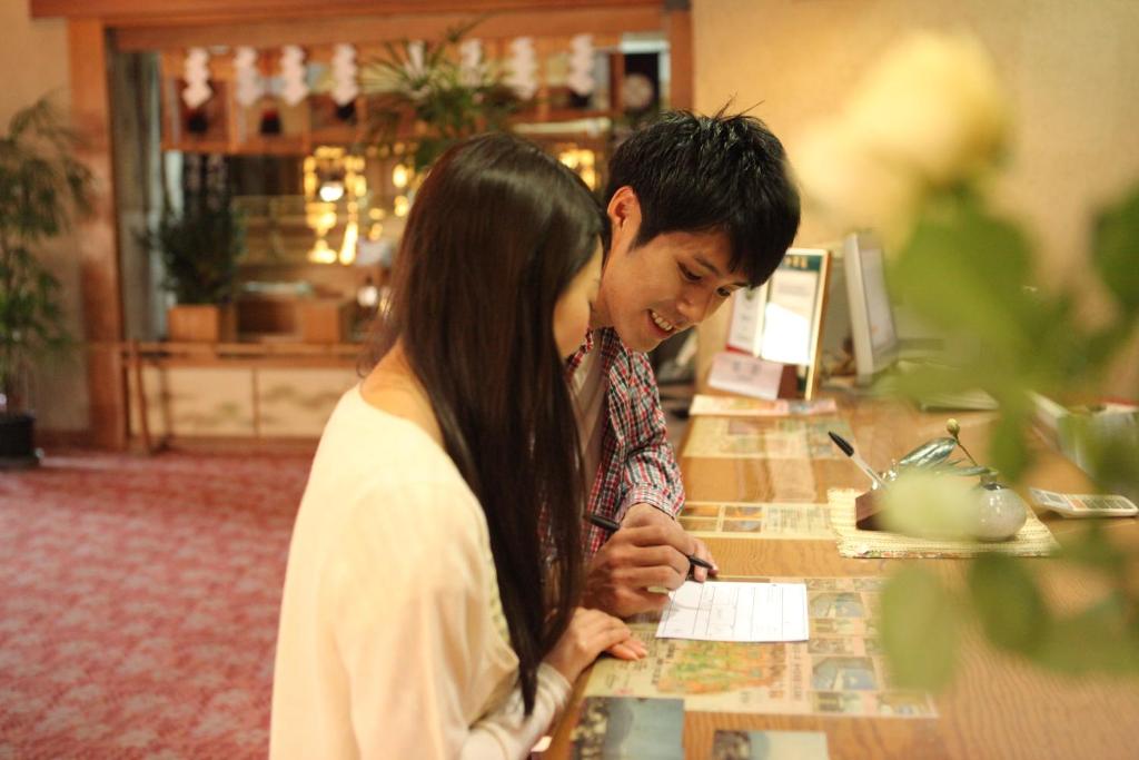 un homme et une femme debout à un comptoir dans l'établissement Hotel Kaminoyu Onsen, à Kai