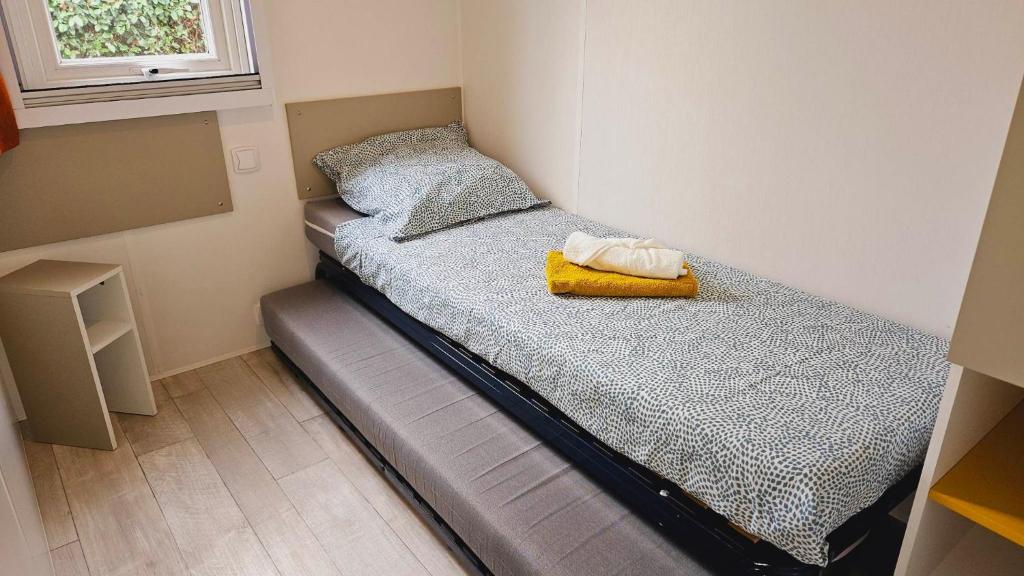 - un petit lit dans une petite chambre avec fenêtre dans l'établissement Joli Mobil home N°11, 4ch tout confort et spacieux, à Gastes