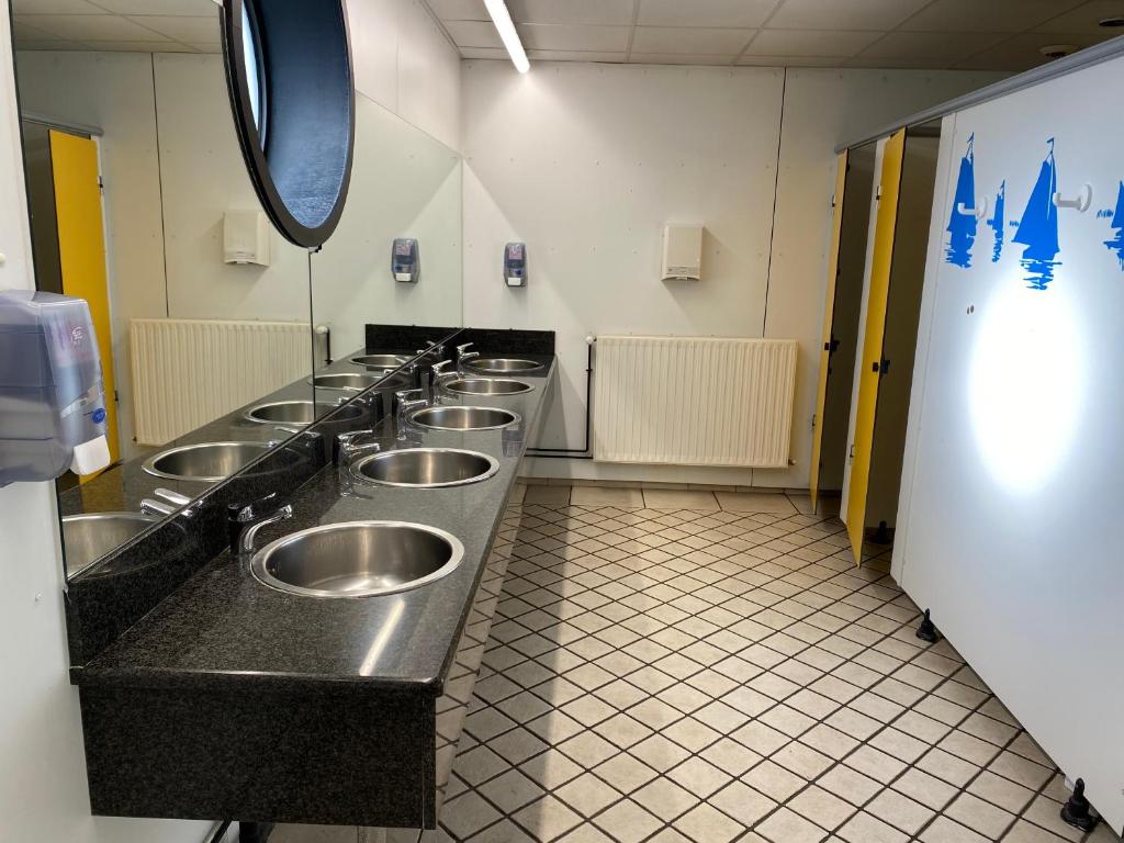 une rangée de lavabos en acier inoxydable dans les toilettes publiques dans l'établissement Nuit insolite à bord du bateau Exocet III, à Boulogne-sur-Mer