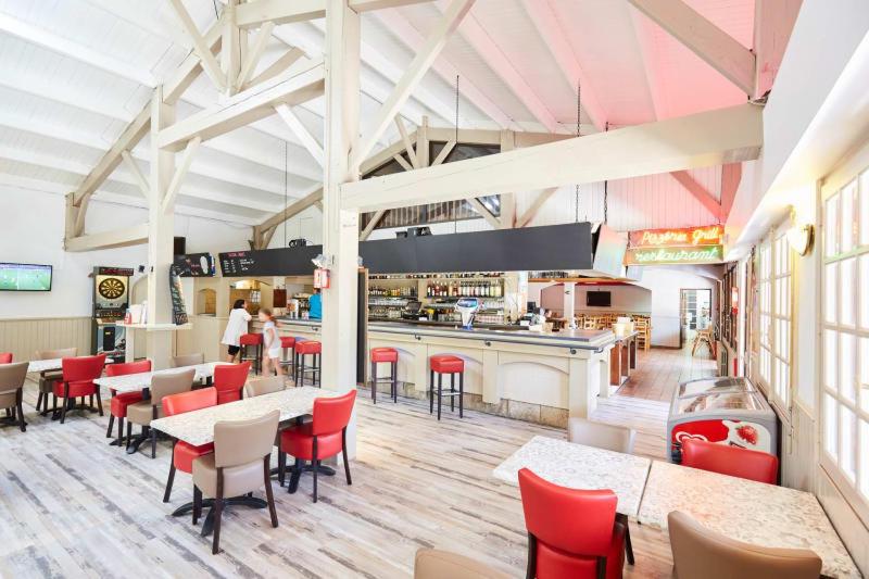 un restaurant avec des chaises et des tables rouges et une cafétéria dans l'établissement Camping Officiel Siblu Le Bois Masson, à Saint-Jean-de-Monts