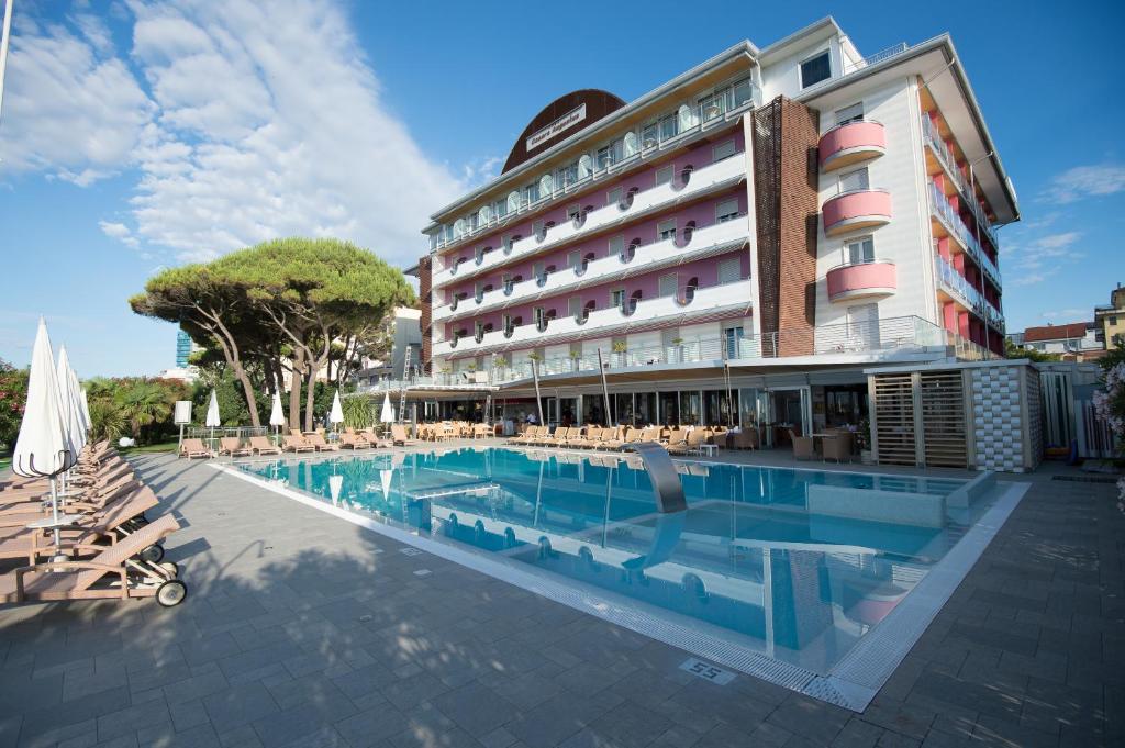 un hôtel avec une piscine devant un bâtiment dans l'établissement Hotel Cesare Augustus, à Lido di Jesolo