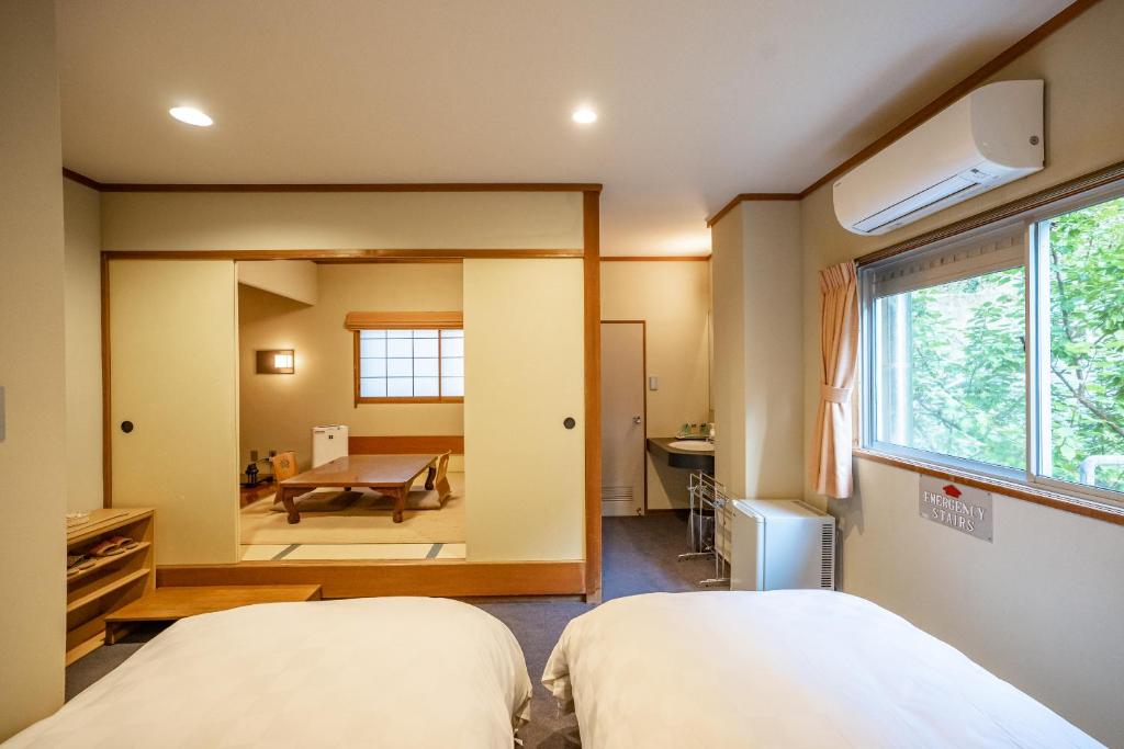 une chambre avec deux lits et un miroir dans l'établissement Shorenkan Yoshinoya, à Kyōtango