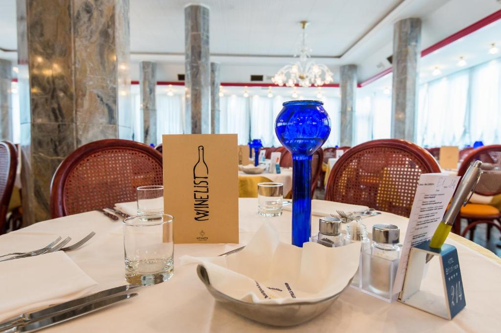 une table dans un restaurant avec un vase bleu en verre dans l'établissement Hotel Brioni Mare, à Lido di Jesolo