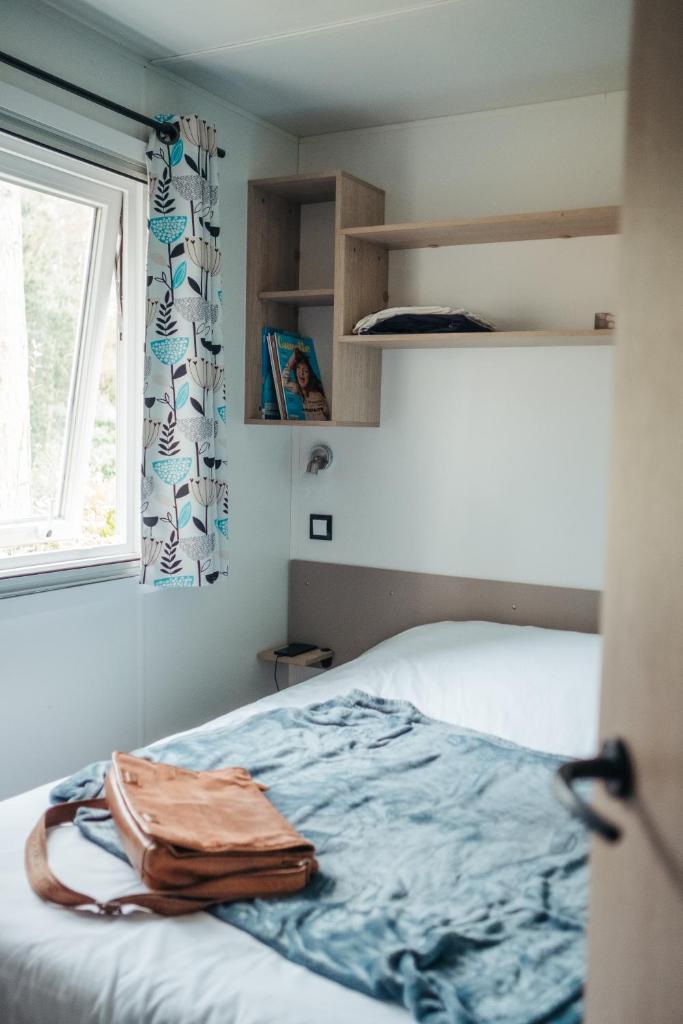 une chambre avec un lit et une fenêtre dans l'établissement Mobil Home XXL 4 chambres - Camping du Vieux Moulin, à Vensac