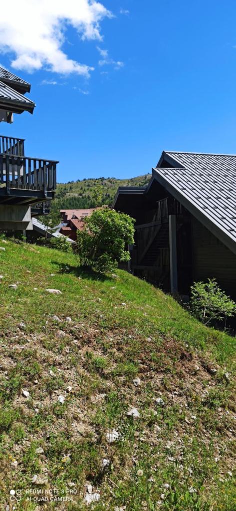 une maison avec une cour herbeuse à côté d'un bâtiment dans l'établissement Appartement duplex au pied des pistes, à Saint-Étienne-en-Dévoluy