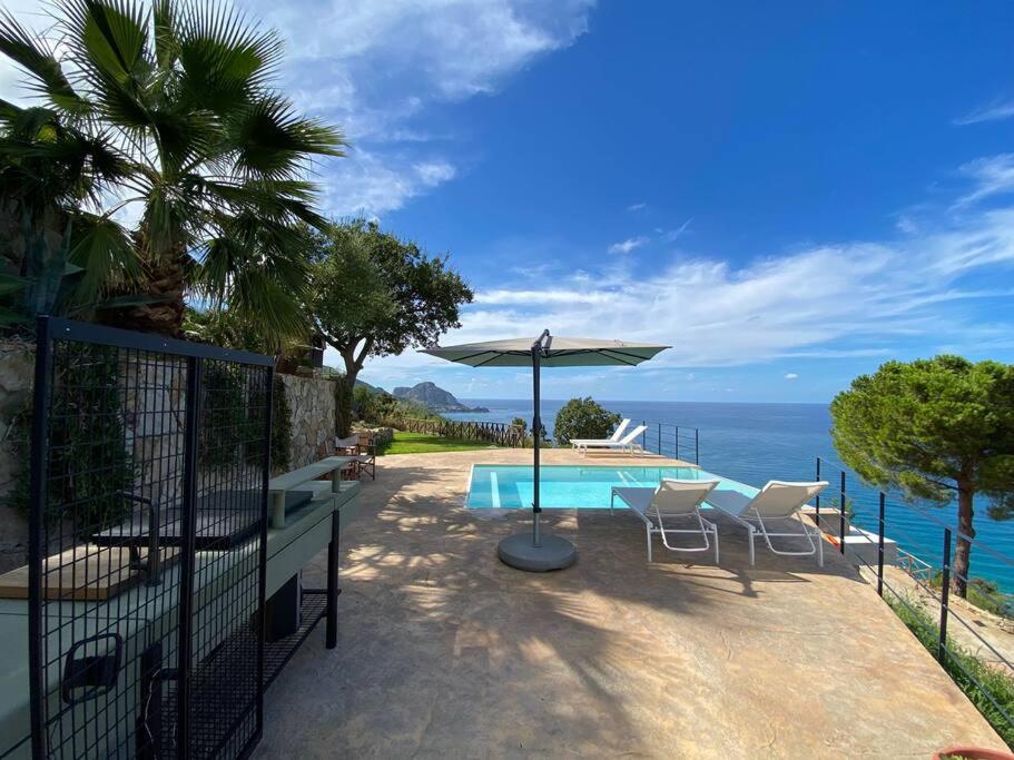 une terrasse avec une table et un parasol et l'océan dans l'établissement Cefalu - luxury seaview villa x10, à Cefalù