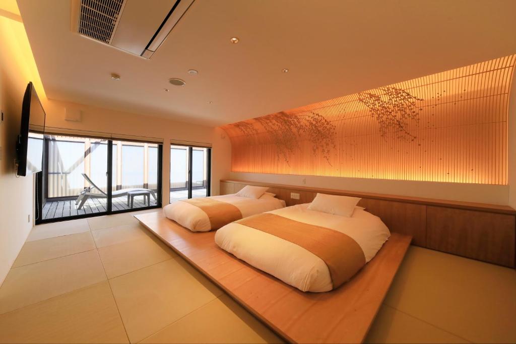 une chambre avec deux lits et une grande fenêtre dans l'établissement Fuji Onsenji Yumedono, à Fujikawaguchiko 37 autres photos