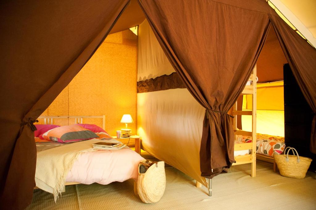 une chambre avec un lit dans une tente dans l'établissement Tente Lodge Bouleau - La Téouleyre, à Saint-Julien-en-Born
