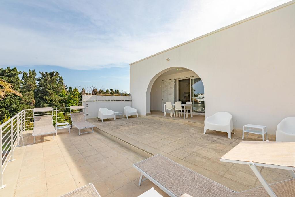 un patio avec des chaises et des tables sur un bâtiment blanc dans l'établissement Villa Arca - RivedelSalento, à Otrante