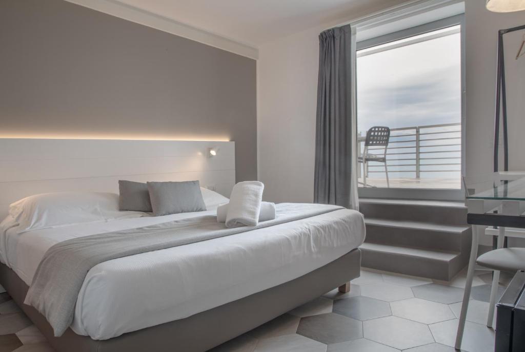 une chambre avec un grand lit et un balcon dans l'établissement Hotel Villa Ambra, à Orbetello