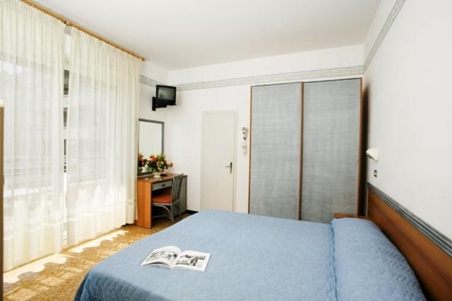 une chambre avec un lit bleu avec deux magazines dessus dans l'établissement Albergo Villa Mauri, à Rimini