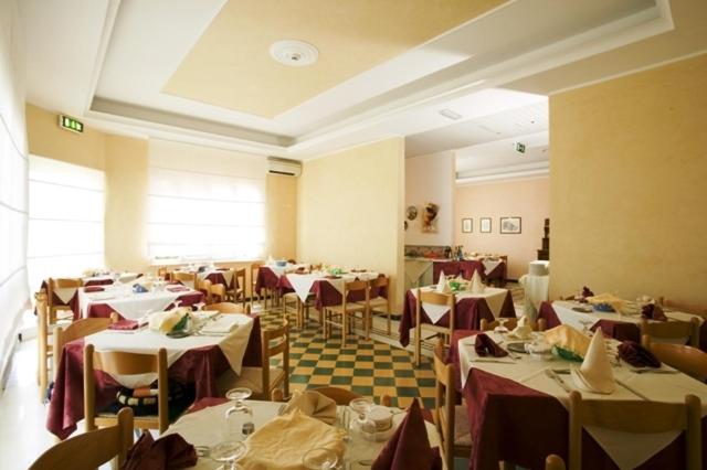 un restaurant avec des tables et des chaises et une salle remplie de tables et de chaises dans l'établissement Albergo Villa Mauri, à Rimini