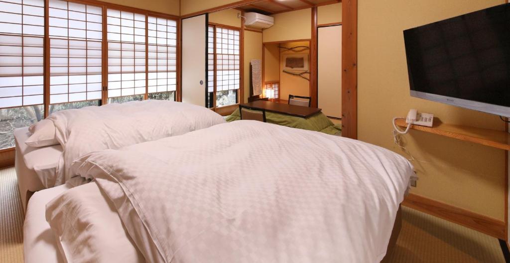 - une chambre à l'hôpital avec un lit et une télévision à écran plat dans l'établissement Yamashinobu, à Minamioguni
