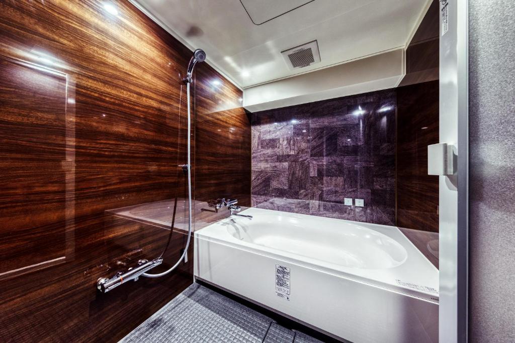 une salle de bain avec baignoire et douche en verre dans l'établissement Hotel Lotus Umeda -Adult Only, à Osaka