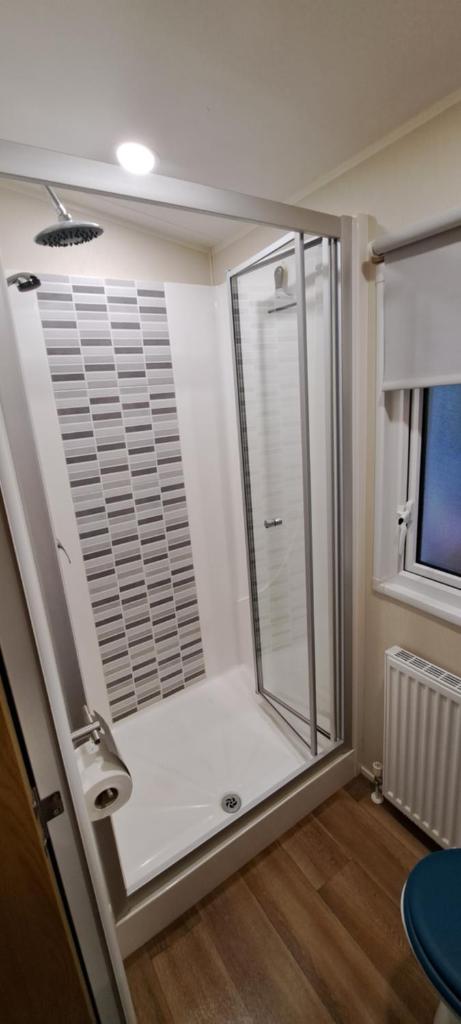 une salle de bain avec une douche avec une porte vitrée dans l'établissement L'Exellence, à Fréjus