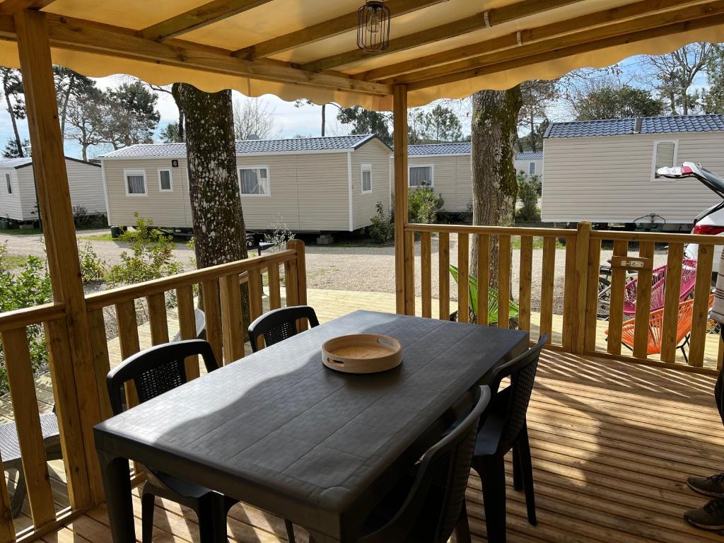 une terrasse couverte en bois avec une table et des chaises. dans l'établissement Cap Rêve, à Lège-Cap-Ferret