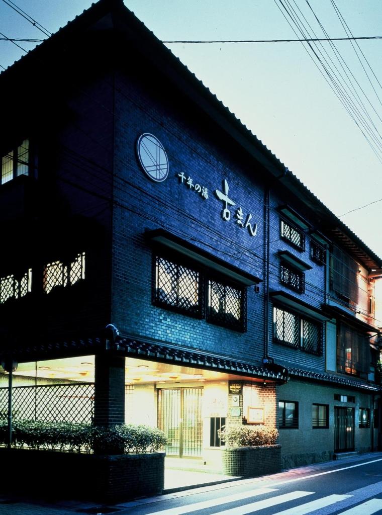 un bâtiment bleu avec une horloge sur son côté dans l'établissement Sennennoyu Koman, à Toyooka