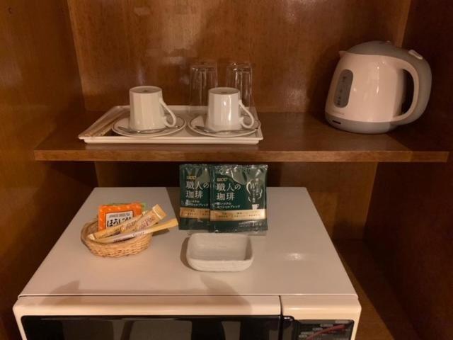- un petit réfrigérateur avec 2 assiettes et des tasses sur une étagère dans l'établissement Hotel HANAMIZUKI-Adult Only, à Otaru