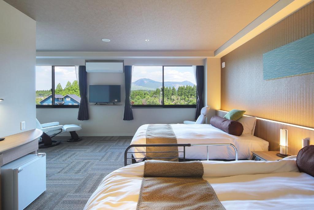 une chambre d'hôtel avec deux lits et une grande fenêtre dans l'établissement Aso Hakuun Sanso, à Aso
