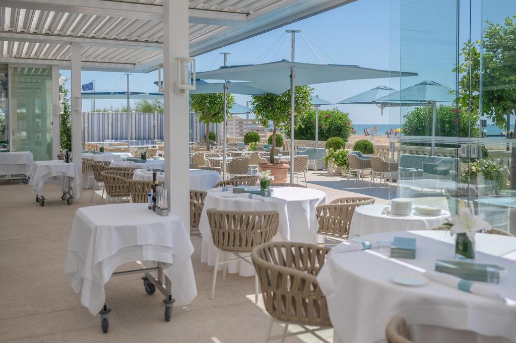 un restaurant avec des tables blanches, des chaises et des parasols dans l'établissement Casa Bianca Al Mare, à Lido di Jesolo
