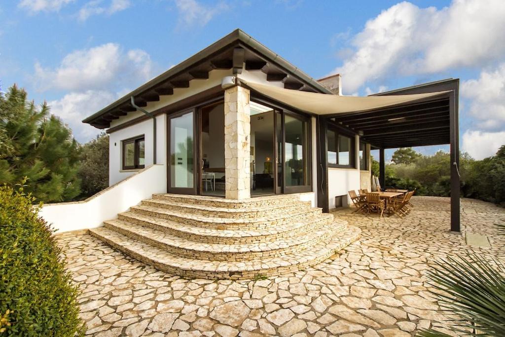 une petite maison avec une passerelle en pierre menant à elle dans l'établissement ClickSardegna Villa Paraiba fronte mare per 12 persone, à Alghero