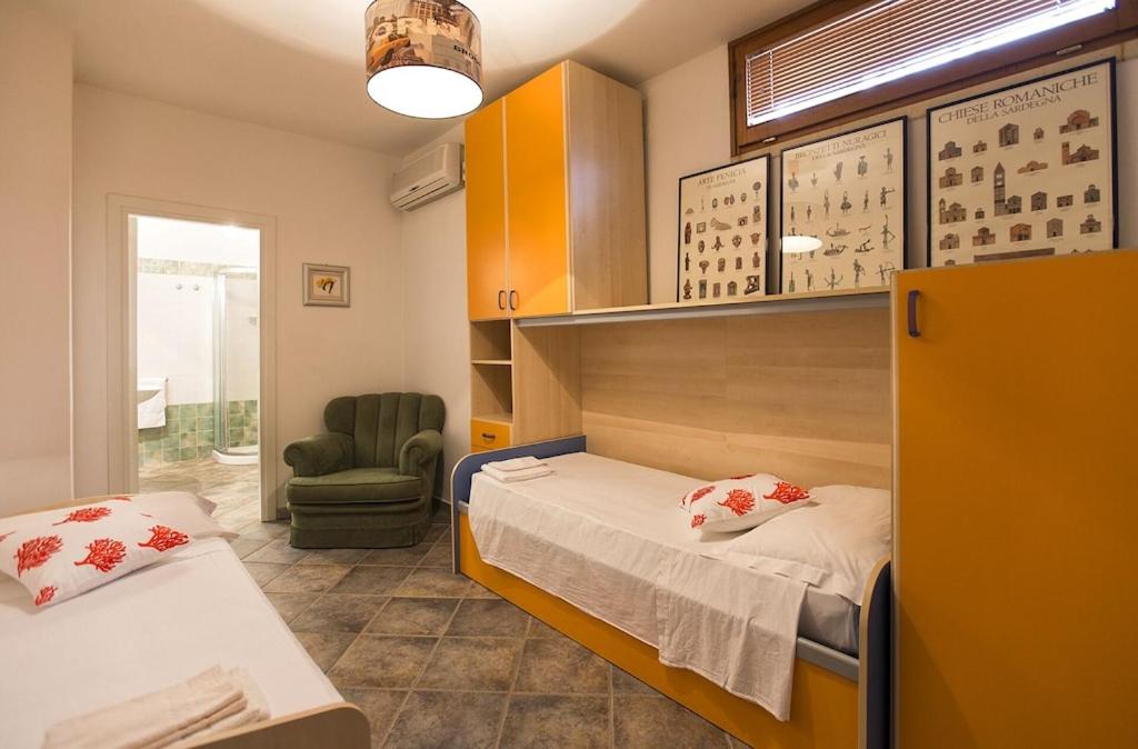 une chambre d'hôpital avec deux lits et une chaise dans l'établissement ClickSardegna Villa Paraiba fronte mare per 12 persone, à Alghero