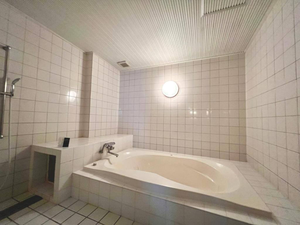 une baignoire dans une salle de bain carrelée blanche dans l'établissement SKY Bali Style Beppu, Resort Love Hotel, à Beppu