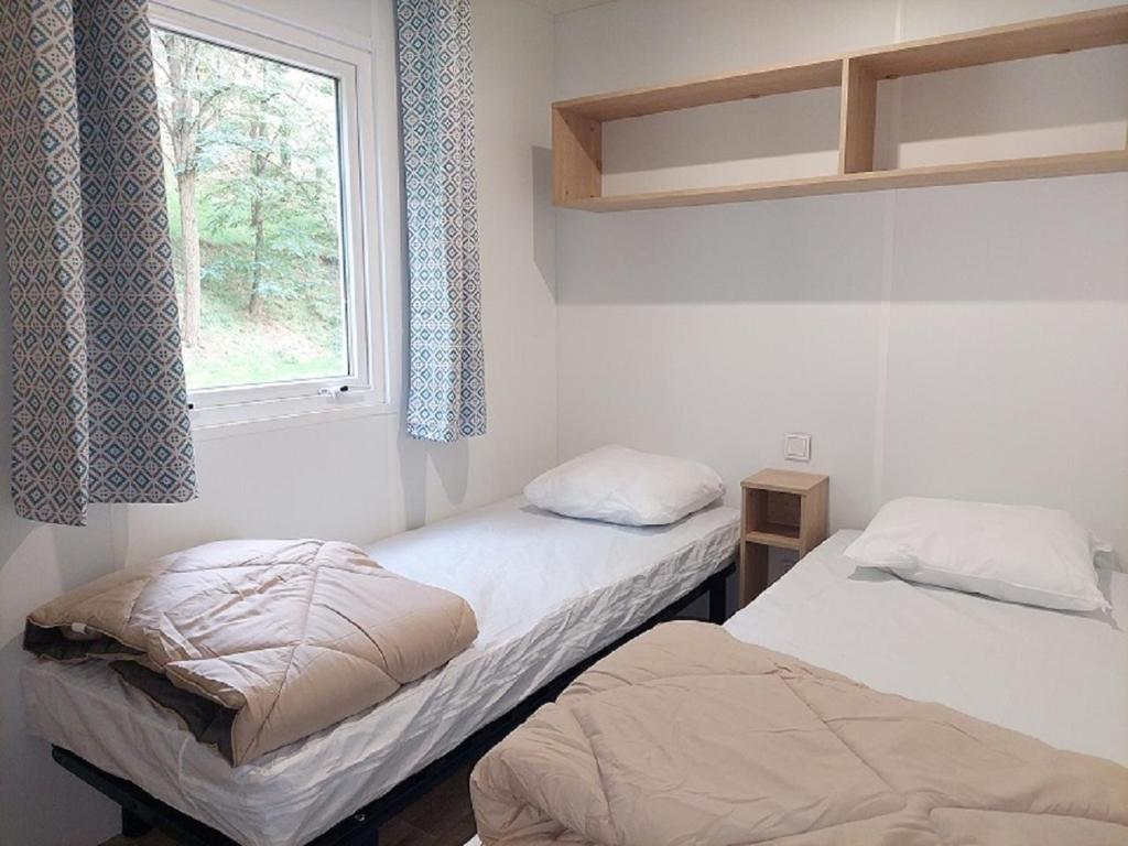 deux lits dans une chambre avec une fenêtre dans l'établissement Camping de Retourtour, à Lamastre