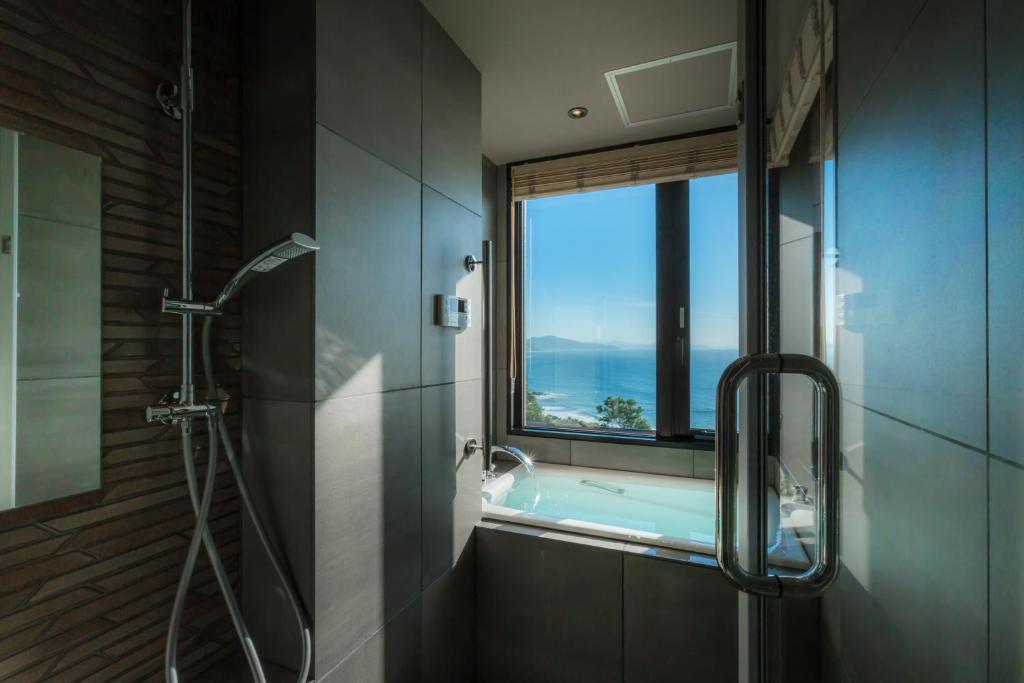 La salle de bains est pourvue d'une douche et d'une fenêtre avec une baignoire. dans l'établissement Jukaitei, à Kyōtango