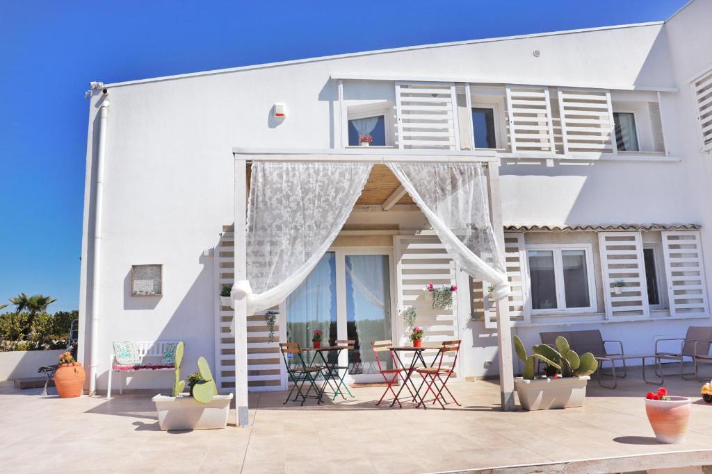 Cette maison blanche dispose d'une terrasse avec des chaises et des tables. dans l'établissement Charme Ibleo - Casa di campagna in Sicilia, à Raguse