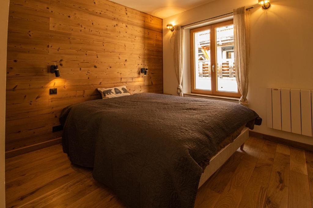 - une chambre avec un lit et un mur en bois dans l'établissement Chalet Peak Noir entier 12pers - Cosy House Peak Noir for 12people, au Monêtier-les-Bains