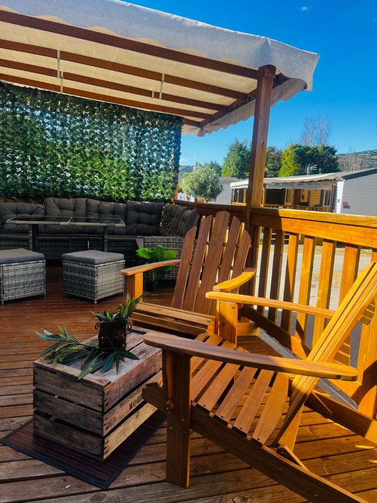 une terrasse avec deux chaises en bois et une pergola dans l'établissement Mobil-home COSY clim&tv-3 Chambres, à Vic-la-Gardiole