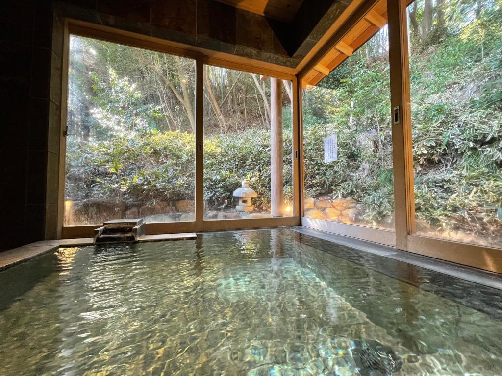 une piscine à débordement dans une maison avec une grande fenêtre dans l'établissement Izuajiro-onsen Shoufuen, à Atami