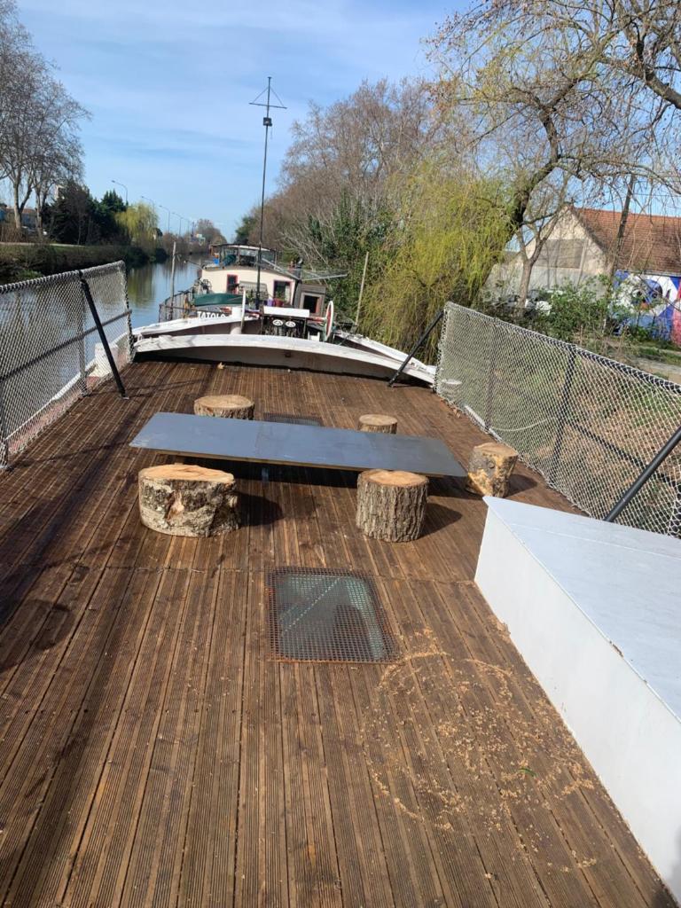 une terrasse en bois avec un banc sur un bateau dans l'établissement chambres dans peniche un air de vacances, à Toulouse 7 autres photos
