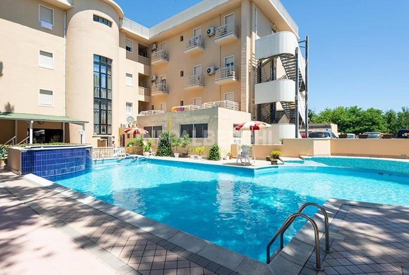 une grande piscine devant un immeuble dans l'établissement Hotel Manila, à Cervia